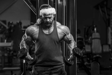 Spor salonunda Noel Baba kostümlü vücut geliştirici.