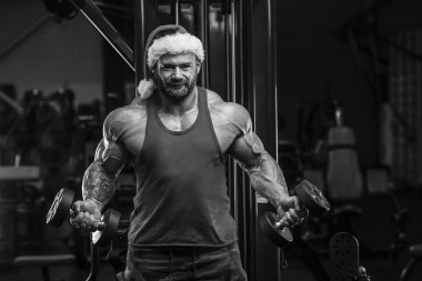 Spor salonunda Noel Baba kostümlü vücut geliştirici.