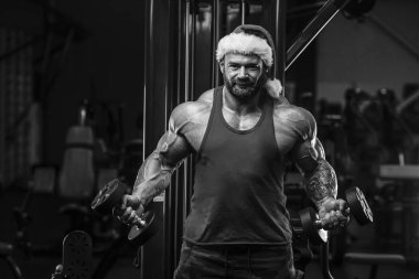 Spor salonunda Noel Baba kostümlü vücut geliştirici.