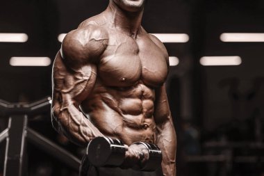 Yakışıklı, güçlü atletik adam kaslarını şişiriyor.