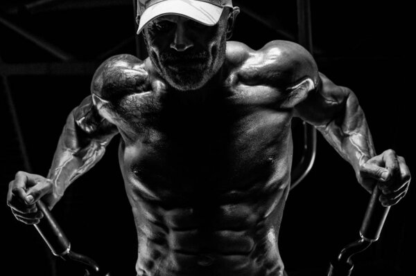 Красивые атлетичные мужчины накачивают мышцы отжиманиями на неровных прутьях
