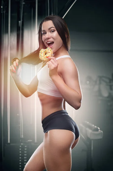 Fitness woman with donut at workout in the gym — Stock Photo, Image