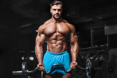 Bodybuilder strong man pumping up biceps muscles