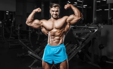 Bodybuilder strong man pumping up biceps muscles