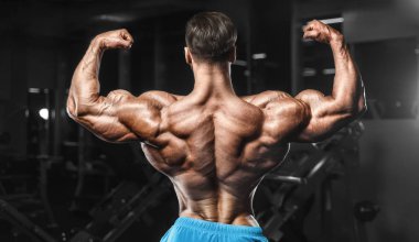 Bodybuilder strong man pumping up biceps muscles
