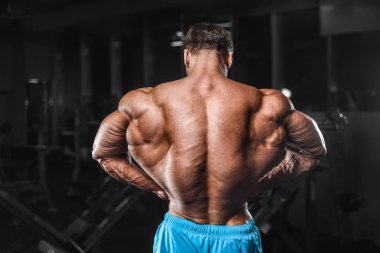 Bodybuilder strong man pumping up biceps muscles