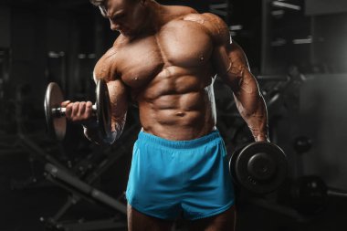 Bodybuilder strong man pumping up biceps muscles