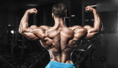 Bodybuilder strong man pumping up biceps muscles