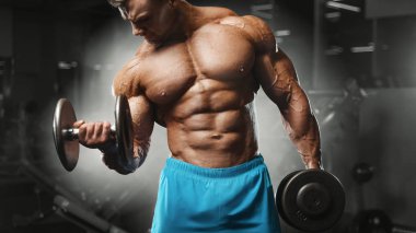 Bodybuilder strong man pumping up biceps muscles