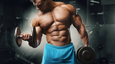 Bodybuilder strong man pumping up biceps muscles
