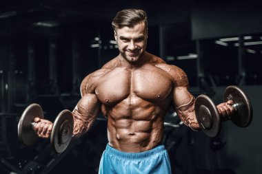 Bodybuilder strong man pumping up biceps muscles