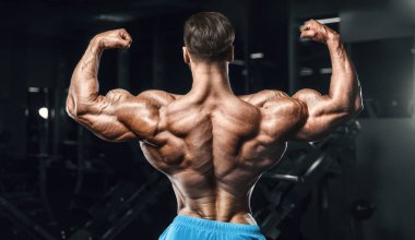 Bodybuilder strong man pumping up biceps muscles