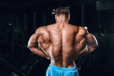 Bodybuilder strong man pumping up biceps muscles