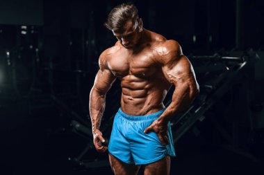 Bodybuilder strong man pumping up abs muscles