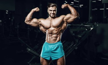 Bodybuilder strong man pumping up biceps muscles