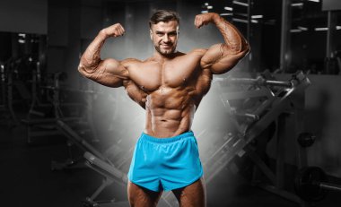 Bodybuilder strong man pumping up biceps muscles
