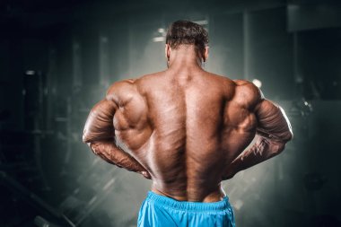 Bodybuilder strong man pumping up biceps muscles