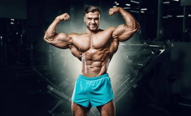 Bodybuilder strong man pumping up biceps muscles