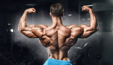 Bodybuilder strong man pumping up biceps muscles