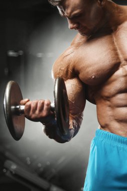 Bodybuilder strong man pumping up biceps muscles