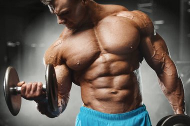 Bodybuilder strong man pumping up biceps muscles