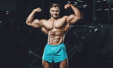Bodybuilder strong man pumping up biceps muscles