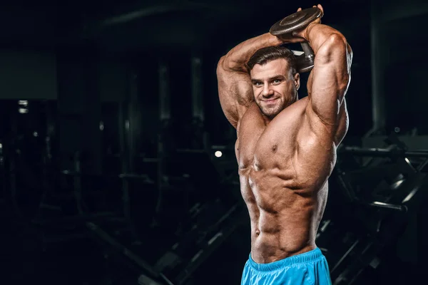 Bodybuilder strong man pumping up triceps muscles — Stok fotoğraf