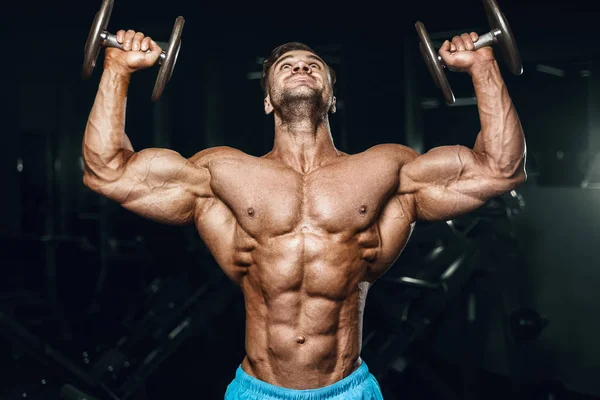 Bodybuilder strong man pumping up shoulder muscles — Stok fotoğraf