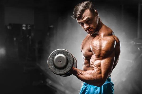 Bodybuilder strong man pumping up biceps muscles — Stok fotoğraf