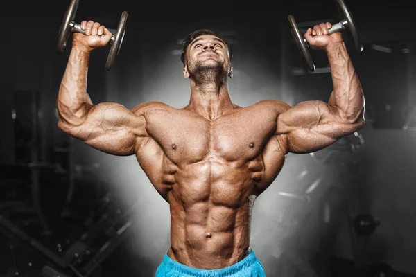 Bodybuilder strong man pumping up shoulder muscles — Stok fotoğraf