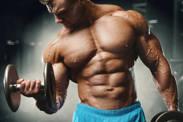 Bodybuilder strong man pumping up biceps muscles — ストック写真