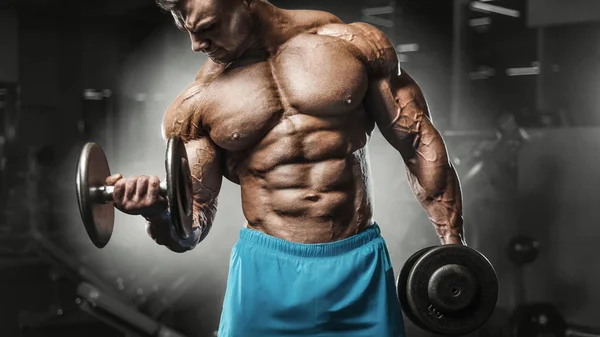 Bodybuilder strong man pumping up biceps muscles — Stok fotoğraf