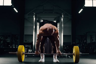 Vücut geliştirici güçlü atletik adam kaslarını şişiriyor.