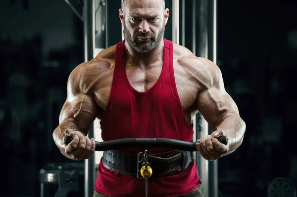 Bodybuilder strong man pumping up biceps muscles — Stockfoto