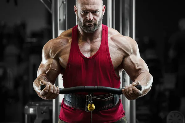 Bodybuilder strong man pumping up biceps muscles — Stok fotoğraf