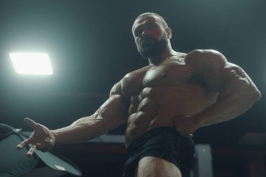 Vücut geliştirici yakışıklı güçlü atletik sert adam karın kaslarını şişiriyor kasları çalıştırıyor vücut geliştirme ve sağlıklı bir konsept geliştirme geçmişi var - kaslı fitness adamları spor salonunda çıplak gövde egzersizleri yapıyor.
