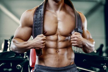 Vücut geliştiren yakışıklı, güçlü, kaslarını şişiren, kas geliştiren, vücut geliştiren, spor kemeri geliştiren, kaslı spor yapan, karın egzersizi yapan, çıplak vücutlu, kaslı sporcu.