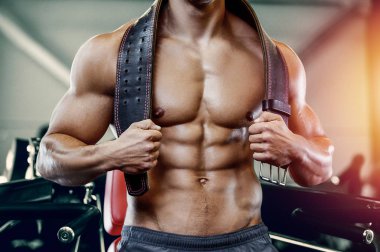 Vücut geliştiren yakışıklı, güçlü, kaslarını şişiren, kas geliştiren, vücut geliştiren, spor kemeri geliştiren, kaslı spor yapan, karın egzersizi yapan, çıplak vücutlu, kaslı sporcu.