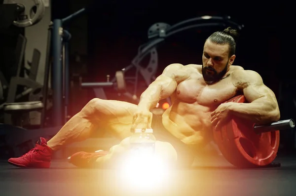 トレーニングフィットネスとボディビルディングの健康的なコンセプトの背景の後にタンパク質粉末と強力な運動神経の男を構築 ジム裸の胴で演習を行う筋肉フィットネスの男性 — ストック写真
