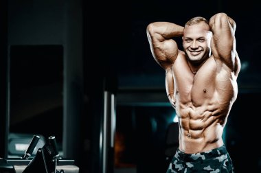 Vücut geliştirici yakışıklı güçlü atletik sert adam karın kaslarını şişiriyor kasları çalıştırıyor vücut geliştirme ve sağlıklı bir konsept geliştirme geçmişi var - kaslı fitness adamları spor salonunda çıplak gövde egzersizleri yapıyor.