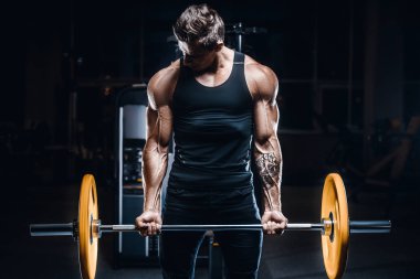 Vücut geliştirici yakışıklı güçlü atletik sert adam kaslarını şişiriyor kaslarını çalıştırıyor sağlıklı bir vücut geliştirme konsepti geliştiriyor kaslı fitness adamları spor salonunda çıplak bedende kol egzersizleri yapıyor.