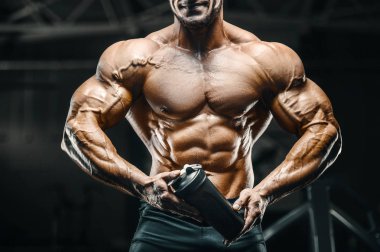 Vücut geliştirici güçlü atletik sert adam egzersiz yaptıktan sonra protein tozuyla vücut geliştirme ve sağlıklı konsept arka planı - kaslı fitness adamları spor salonunda çıplak gövde egzersizleri yapıyor.