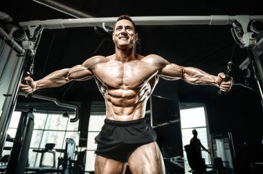 Kablolu TV 'deki kaslı vücut geliştirici fitness adamları kaslarını şişiriyor. Vücut geliştirme egzersizleri ve vücut geliştirme konsepti - Spor salonunda çıplak vücut egzersizleri yapan yakışıklı atletik erkekler