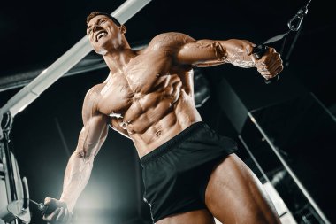 Kablolu TV 'deki kaslı vücut geliştirici fitness adamları kaslarını şişiriyor. Vücut geliştirme egzersizleri ve vücut geliştirme konsepti - Spor salonunda çıplak vücut egzersizleri yapan yakışıklı atletik erkekler