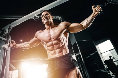 Kablolu TV 'deki kaslı vücut geliştirici fitness adamları kaslarını şişiriyor. Vücut geliştirme egzersizleri ve vücut geliştirme konsepti - Spor salonunda çıplak vücut egzersizleri yapan yakışıklı atletik erkekler