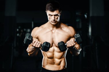 Vücut geliştirici yakışıklı güçlü atletik sert adam kaslarını şişiriyor kaslarını çalıştırıyor sağlıklı bir vücut geliştirme konsepti geliştiriyor kaslı fitness adamları spor salonunda çıplak bedende kol egzersizleri yapıyor.