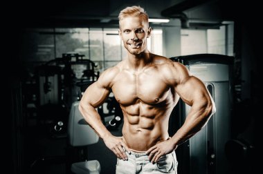 Vücut geliştirici yakışıklı güçlü atletik sert adam karın kaslarını şişiriyor kasları çalıştırıyor vücut geliştirme ve sağlıklı bir konsept geliştirme geçmişi var - kaslı fitness adamları spor salonunda çıplak gövde egzersizleri yapıyor.