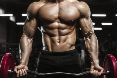Vücut geliştirici yakışıklı güçlü atletik sert adam karın kaslarını şişiriyor kasları çalıştırıyor vücut geliştirme ve sağlıklı bir konsept geliştirme geçmişi var - kaslı fitness adamları spor salonunda çıplak gövde egzersizleri yapıyor.