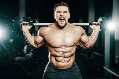 Adam bacak kaslarını şişiriyor vücut geliştirme konsepti spor salonu arka plan egzersizleri spor salonunda çıplak gövde.