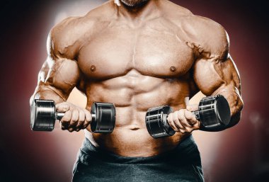 Vücut geliştirici yakışıklı güçlü atletik sert adam kaslarını şişiriyor kaslarını çalıştırıyor sağlıklı bir vücut geliştirme konsepti geliştiriyor kaslı fitness adamları spor salonunda çıplak bedende kol egzersizleri yapıyor.